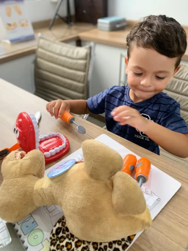 Criança brinca com um modelo de dentes no consultório